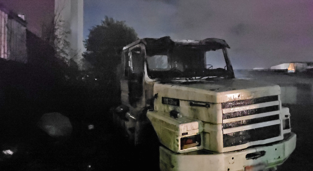 Incêndio atinge caminhão em terreno durante a noite